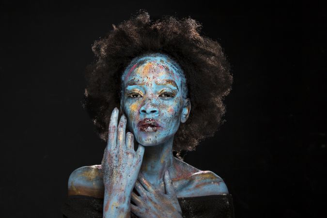 Portrait of woman with afro hair and blue face paint