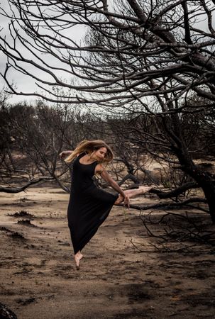 Woman dancing between dry trees