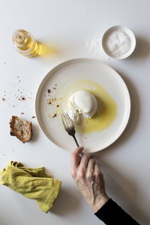 Crop hand taking cheese near bread and oil