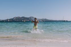 Man in swimsuit running in water on seashore