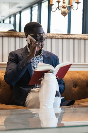 Stylish Black businessman speaking on smartphone on sofa