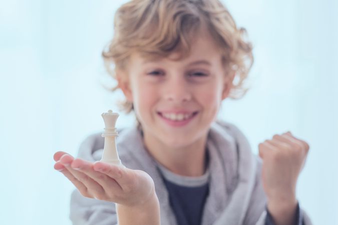 Smiling preteen boy with chess piece of queen on palm