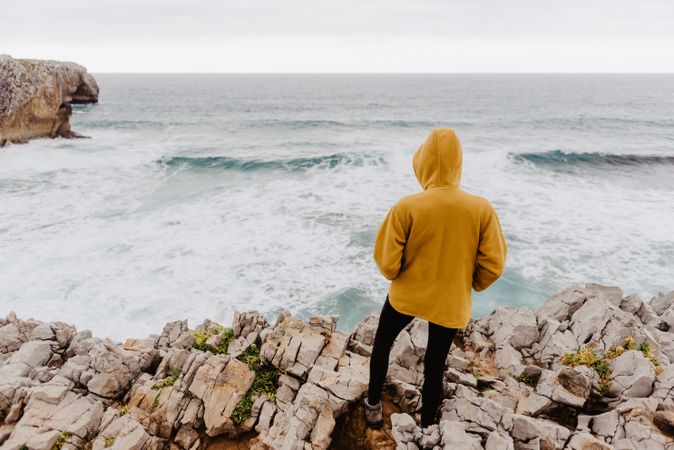 Person in yellow hoodie on stony shore