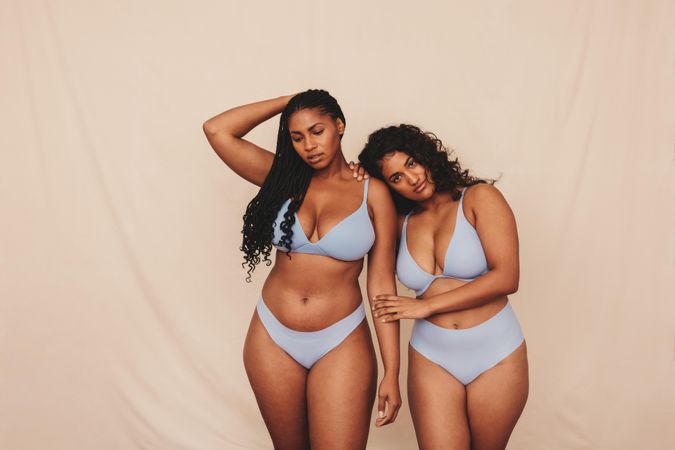 Two body positive young women wearing blue underwear in a studio