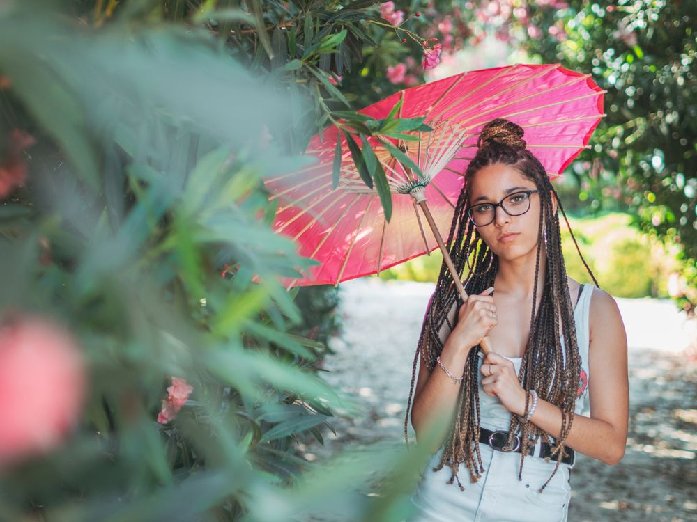 Fit young female with umbrella standing near blooming trees
