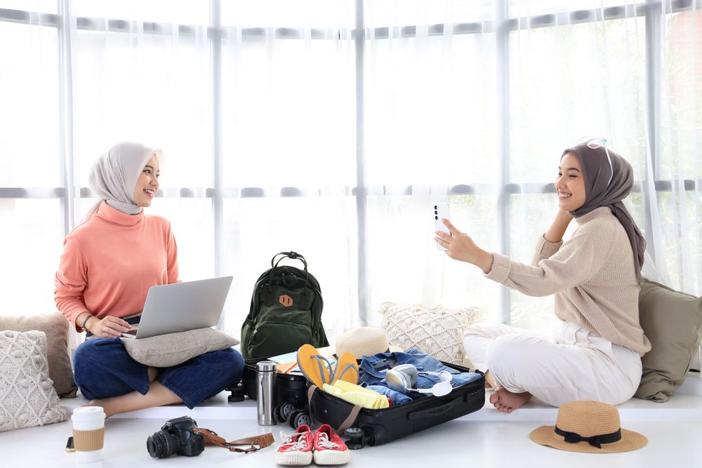Two Young Asian Women Prepare for Summer Trip, Book Tickets Using Laptop and Take Selfies for Today's Outfits