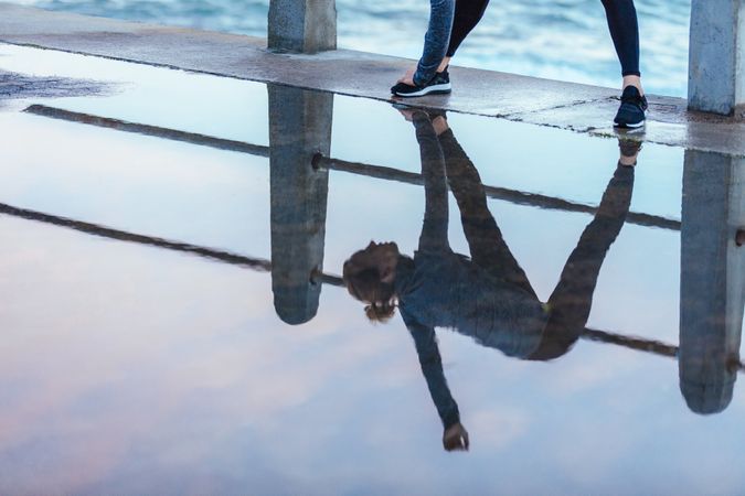 Exercising woman reflection in puddle of water