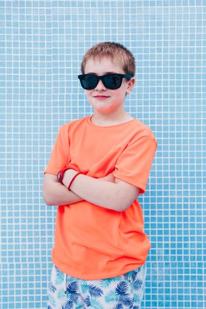Happy boy in sunglasses against tiled wall
