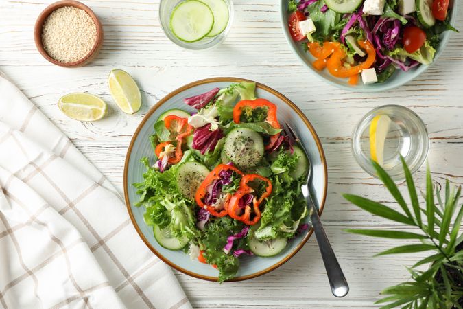 Fresh salads with spices on rustic wooden background, top view