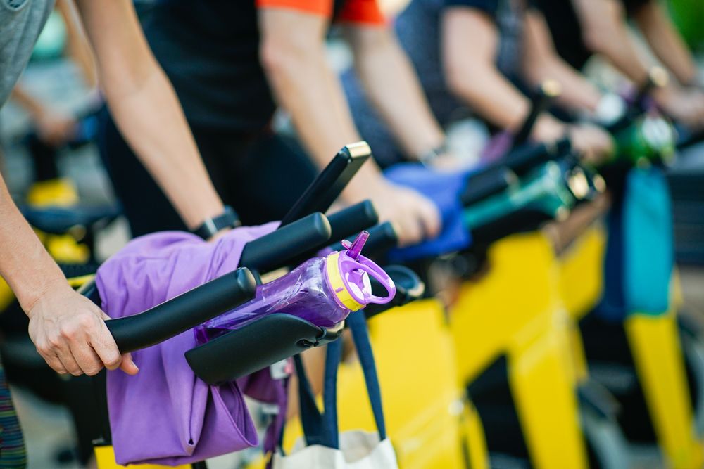 Group of people working out on stationary bikes at spinning class in gym