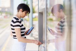 Woman holding phone while taking out money on ATM