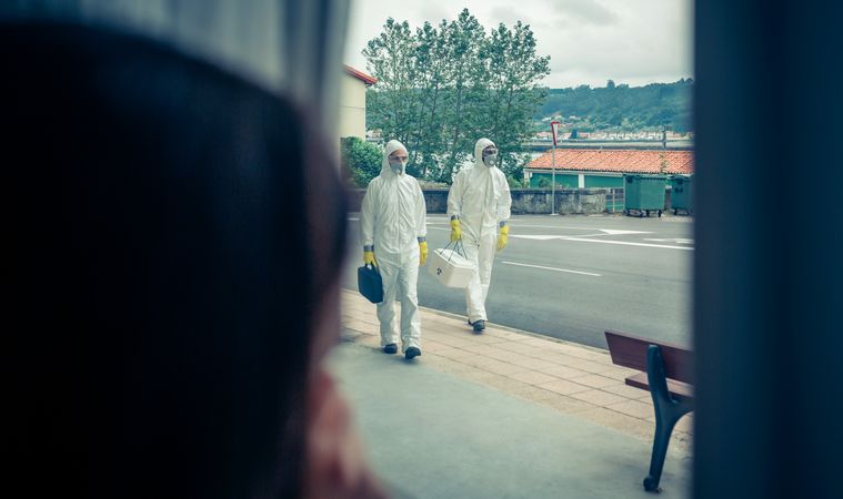 Woman watching through the window people in protection suits
