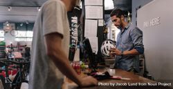Man at the billing counter selling a bicycle helmet bDYQ80