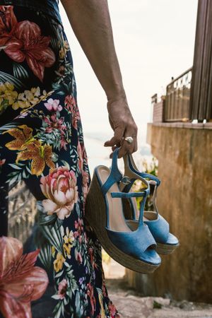 Crop woman holding summer wedge heels