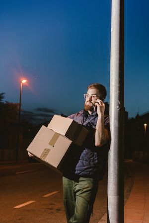 Dedicated courier phoning for delivery completion while waiting client on street in evening