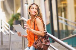 Latina woman using tablet standing in the city