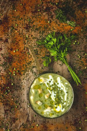 Green vegetable cream soup with crackers and peas in a pan