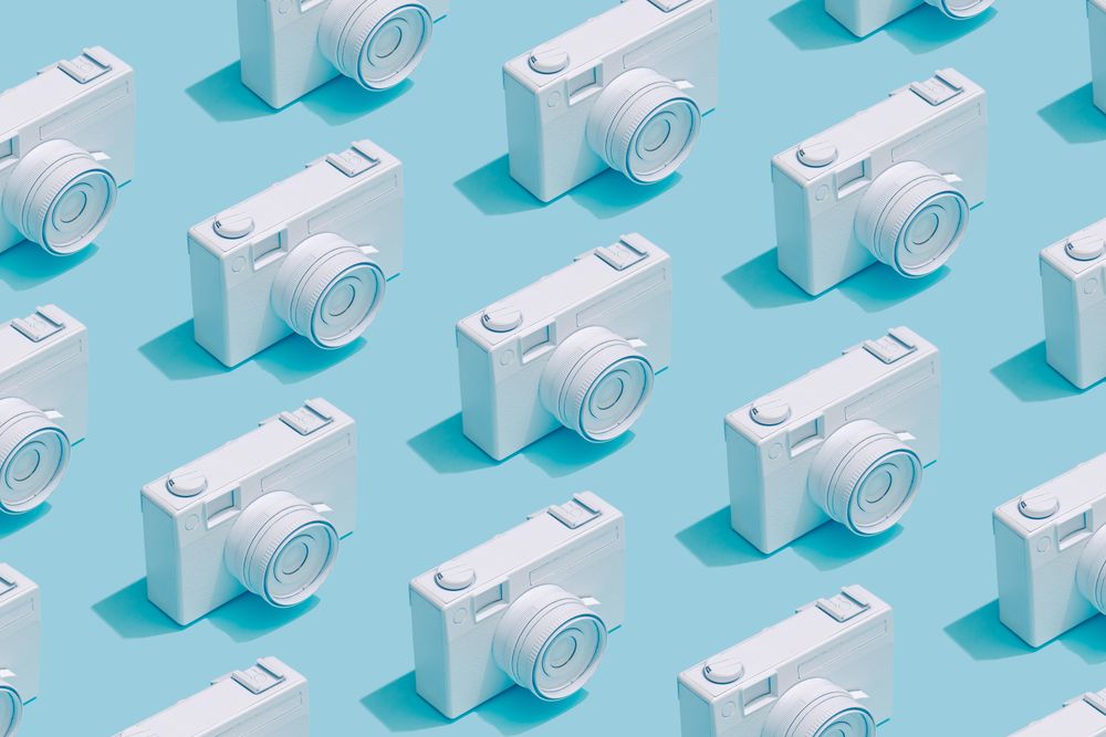 Pattern composition of vintage cameras on pastel blue background