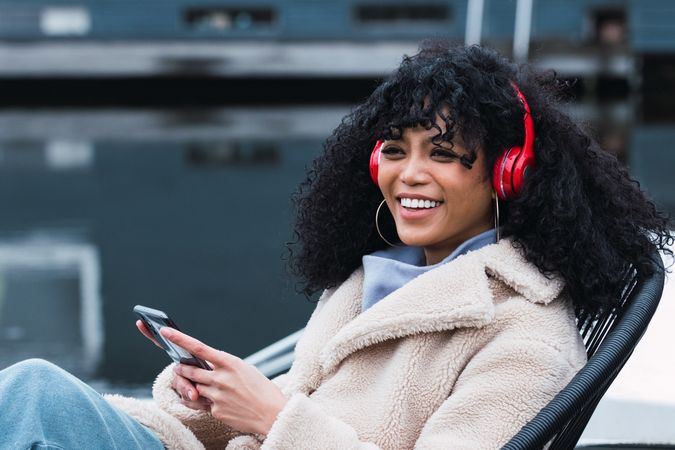 Cheerful woman listening to music at lakeside