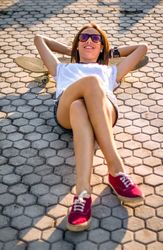 Young girl with a skateboard lying on the street in summer