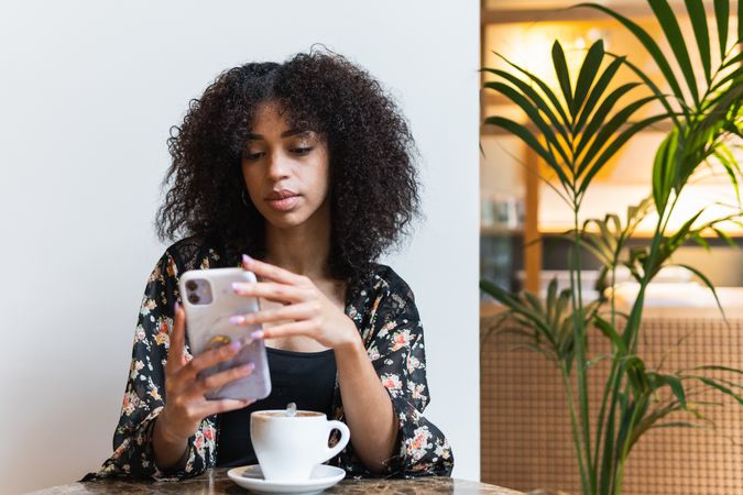 Black woman chatting on smartphone in cafe