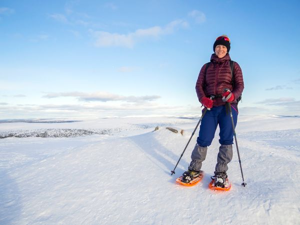 Smiling woman in snow shoes on wintry landscape