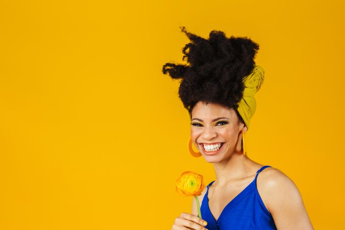 Portrait of happy Black woman with large earrings holding a rose