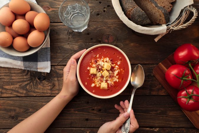 Person hands holding bowl with gazpacho