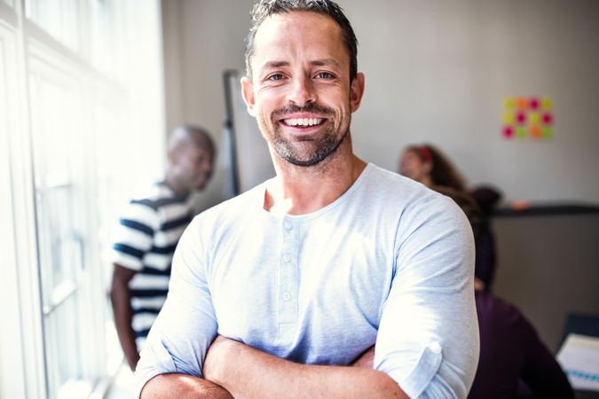 Man smiling in office with arms folded