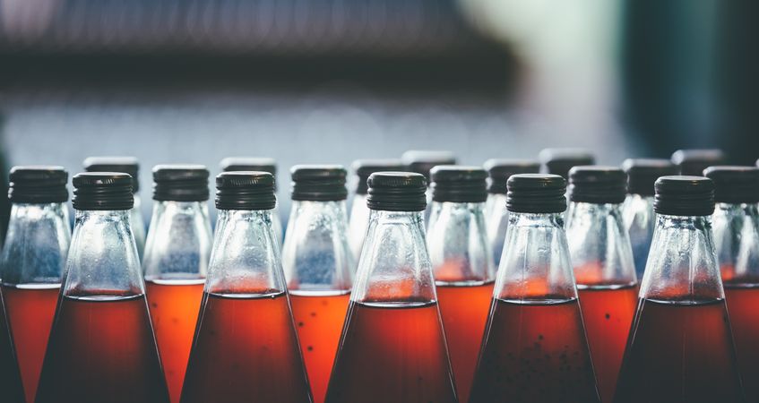 Multiple bottles of fruit juice are arranged in rows, creating a colorful and organized background.