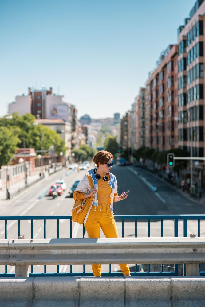 Woman with smartphone standing on road bridge