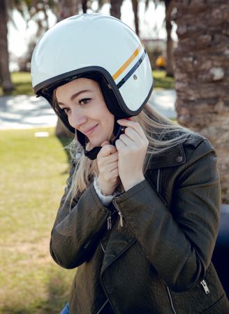 Woman in motorcycle adjusting helmet