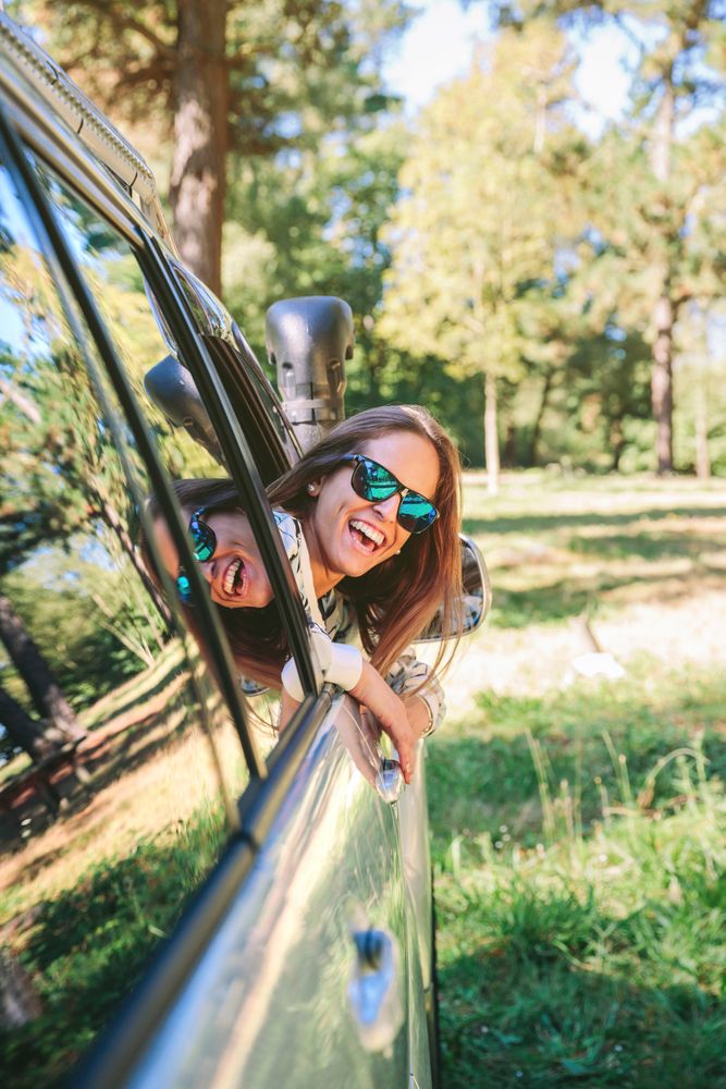 Happy young woman looking back through the window car