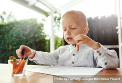 Smiling blond boy drawing outside on deck with crayons 49zvab