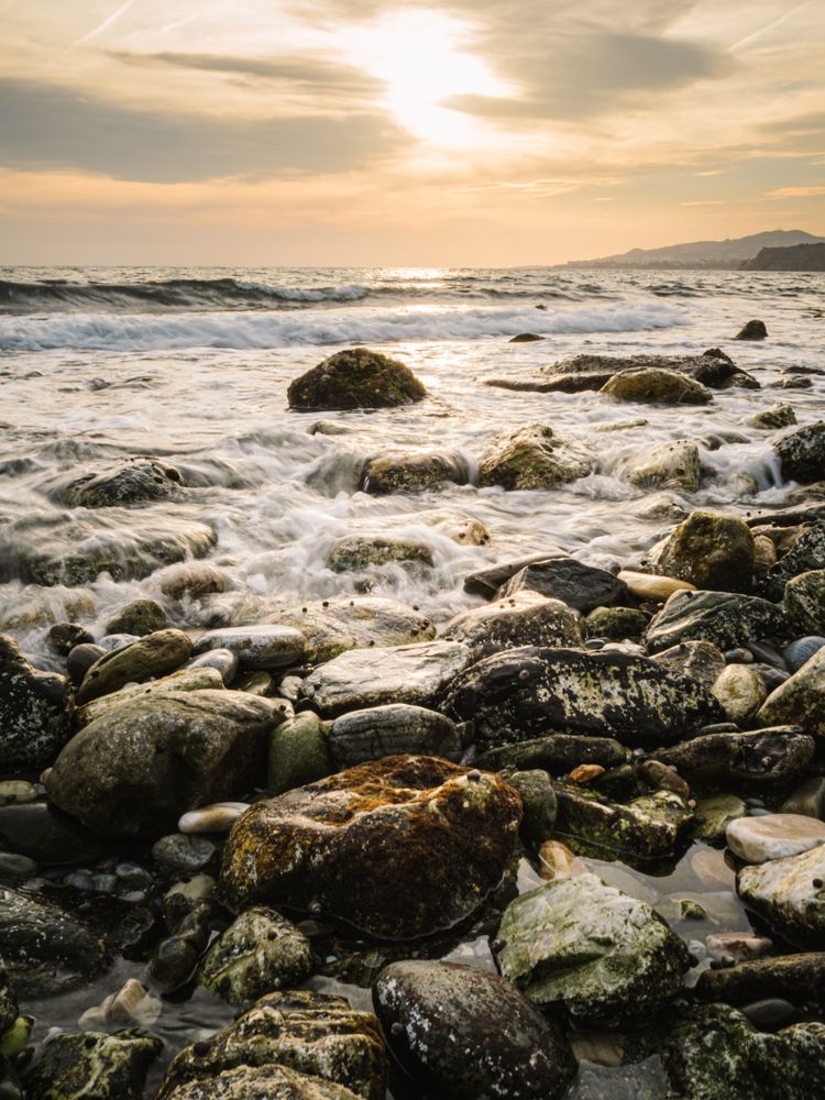 Stony seashore and waves at beautiful sunset