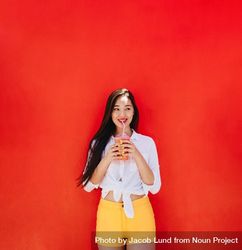 Beautiful woman having a refreshing smoothie against a red wall 41dLO5