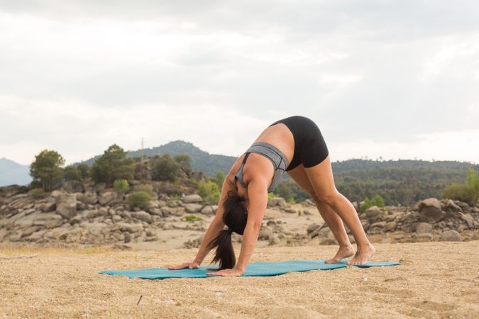 Woman practicing yoga outdoors near water