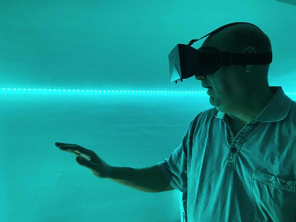 Overwhelmed man wearing virtual reality headset indoor