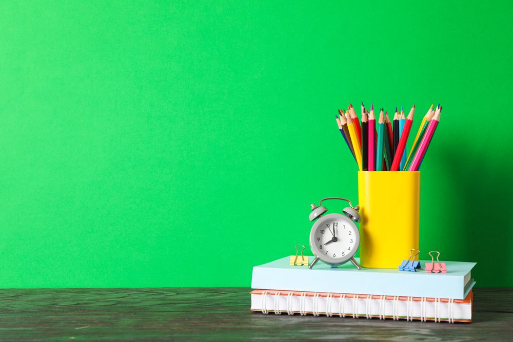 School supplies on wooden table against green background, space for text