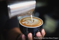 Barista pouring foam and milk to make cappuccino 0KQRN4