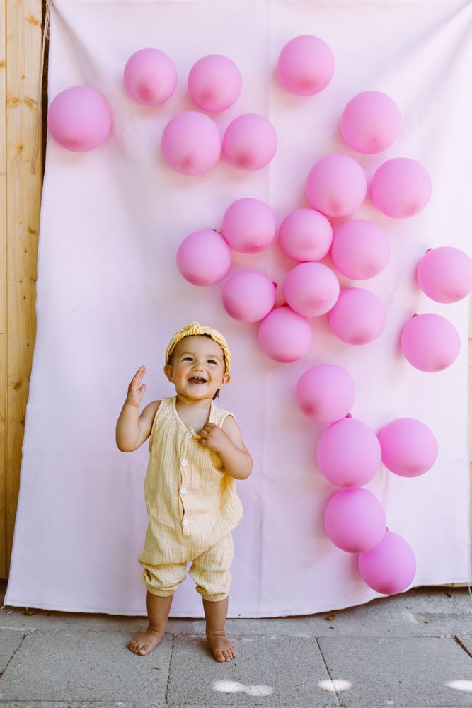 Delighted boy standing near wall with balloons