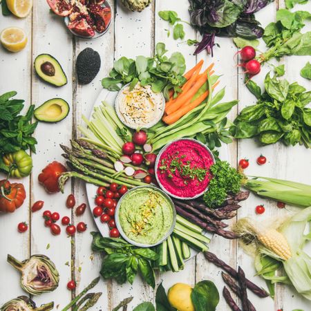 Fresh colorful vegetables and dips with hummus, avocados, asparagus, carrots, square crop