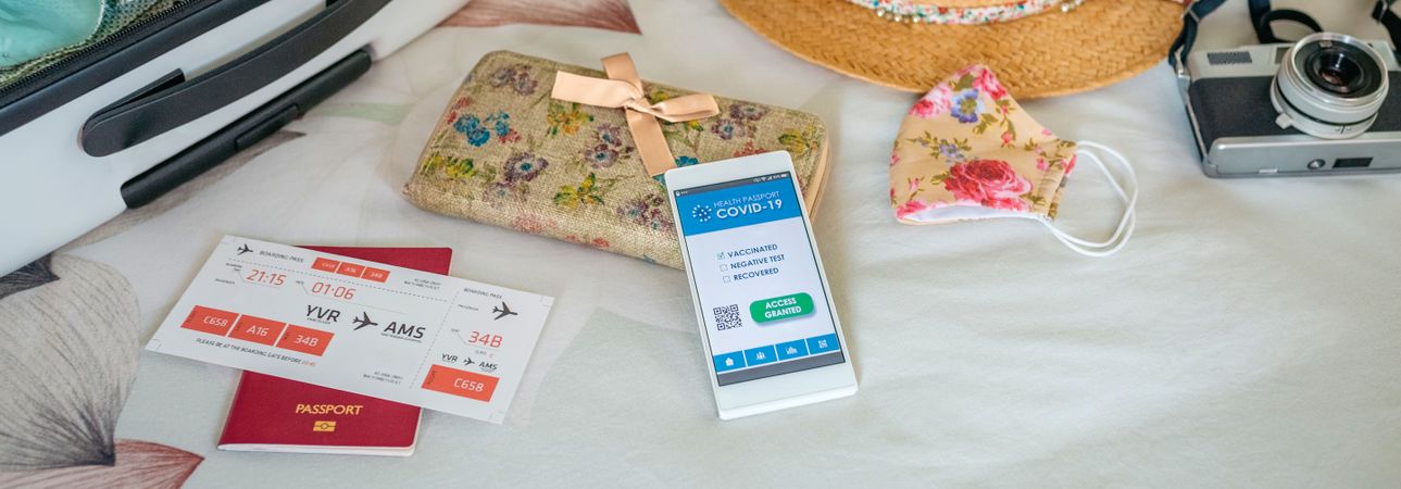 Woman preparing suitcase for vacation and mobile phone with covi