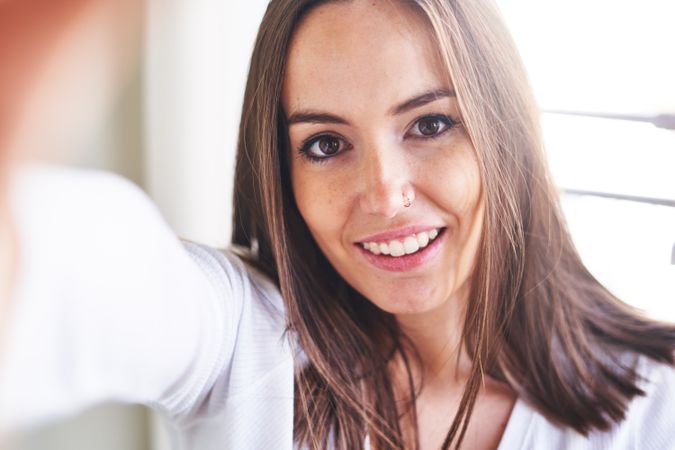Woman showing tongue and taking selfie on smartphone