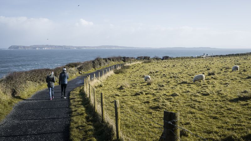 Couple walking on country road between sea and field