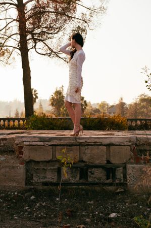 Side view of woman in white dress standing outside on stone wall