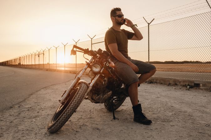 Man sitting on motorcycle and surfing mobile