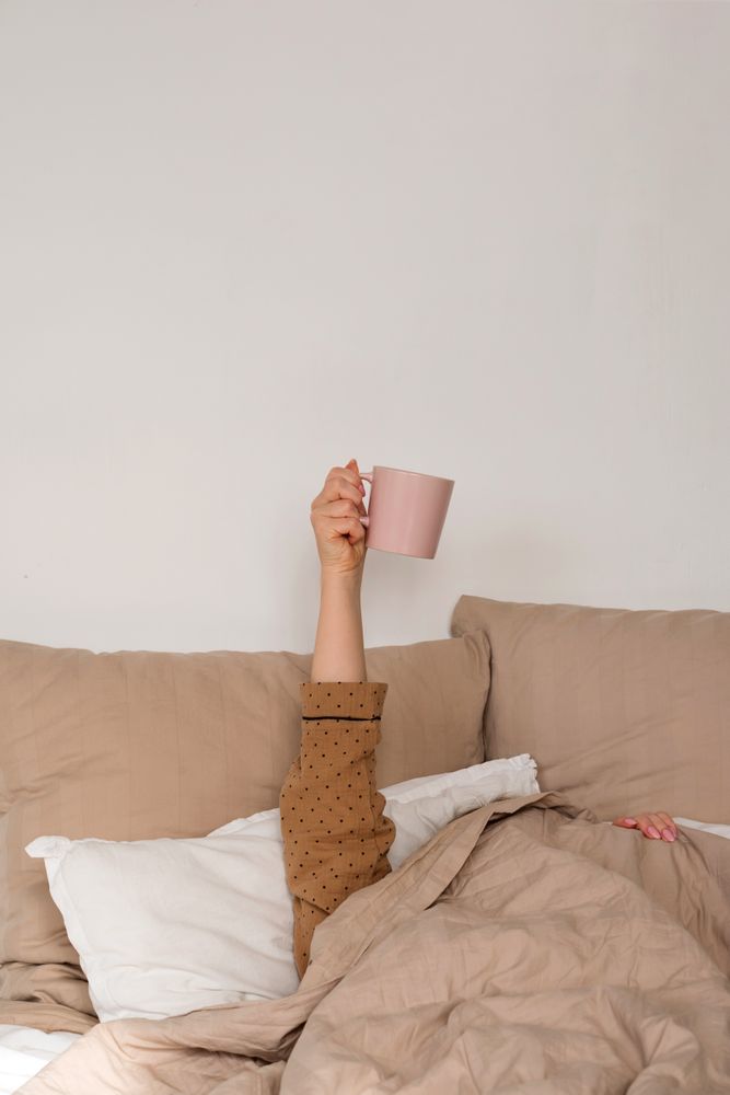 Arm holding coffee mug in bed