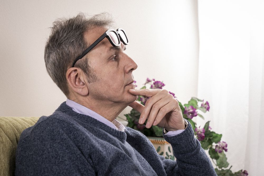 Mature man with flip-up glasses thinking and contemplating at home.