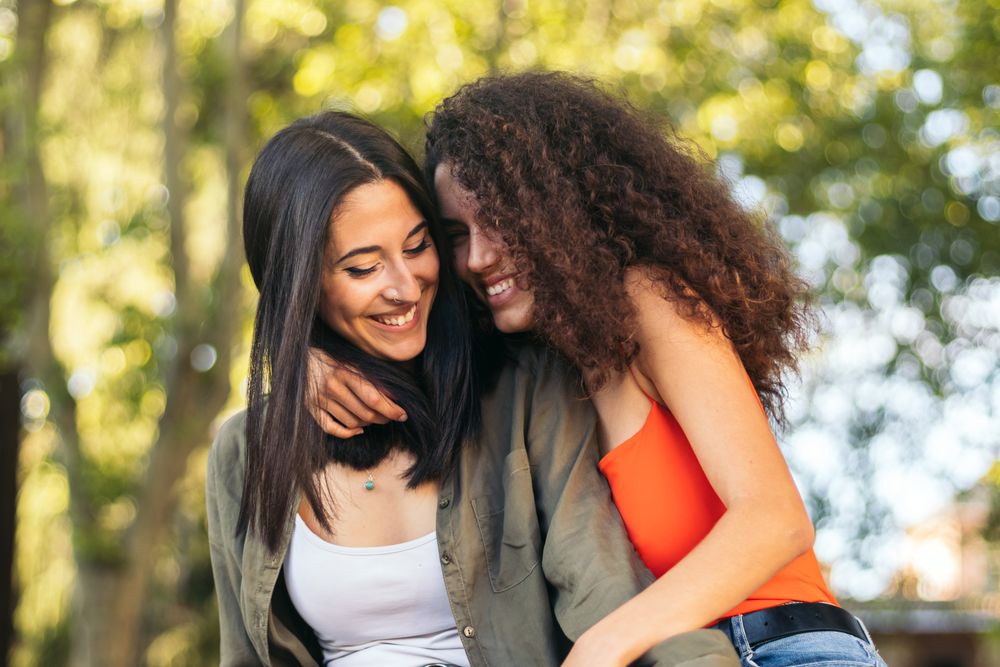 young female couple sitting hugging in a park